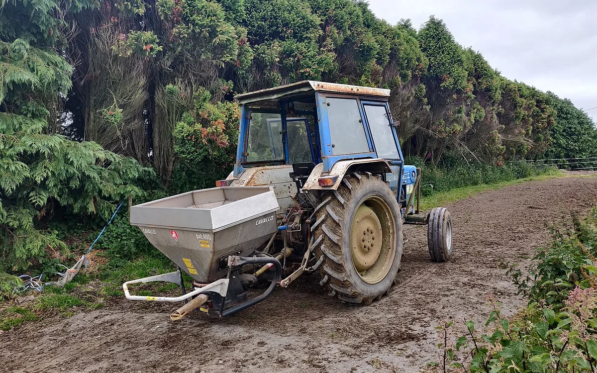 Distribuidor agrícola aplicando adubação nitrogenada em cobertura entre as linhas de milho em fase vegetativa