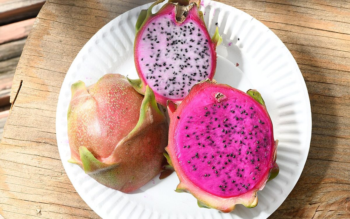 Frutos maduros de pitaia vermelha abertos exibindo polpa magenta e sementes pretas